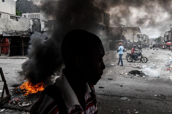 Người đàn ông đi qua lốp xe bị đốt trong cuộc biểu tình ở Port-au-Prince, Haiti - Sputnik Việt Nam