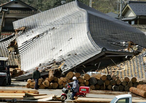 Người đưa thư Nhật Bản lái xe qua các tòa nhà bị hư hại do động đất ở Wajima - Sputnik Việt Nam
