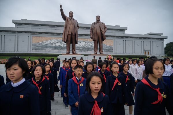Nhóm sinh viên cạnh hai bức tượng của các nhà lãnh đạo Triều Tiên Kim Il Sung và Kim Jong Il bày tỏ sự kính trọng nhân dịp kỷ niệm 74 năm thành lập Đảng Lao động Triều Tiên, CHND Triều Tiên - Sputnik Việt Nam