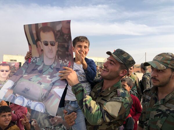 Trẻ em và quân nhân cầm áp phích vẽ chân dung của Tổng thống Syria Bashar al-Assad tại thành phố Manbij được quân đội chính phủ Syria giải phóng - Sputnik Việt Nam