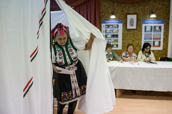 Người phụ nữ mặc trang phục dân tộc rời khỏi phòng bỏ phiếu tại cuộc bầu cử địa phương trên toàn quốc, làng Rimoc, Hungary - Sputnik Việt Nam