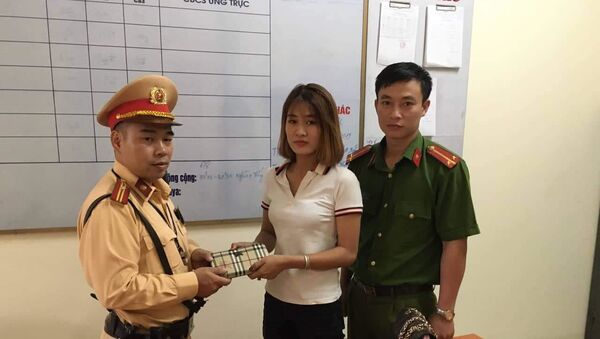 Thiếu tá Nguyễn Minh Tuấn cùng cán bộ Công an thị trấn Văn Điển trao tận tay chiếc ví bên trong có đầy đủ tài sản cho chị Đỗ Phương Anh  - Sputnik Việt Nam