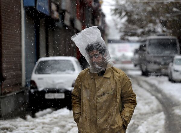 Một người đàn ông che đầu bằng một chiếc túi nhựa trong trận tuyết rơi ở Srinagar, Kashmir - Sputnik Việt Nam