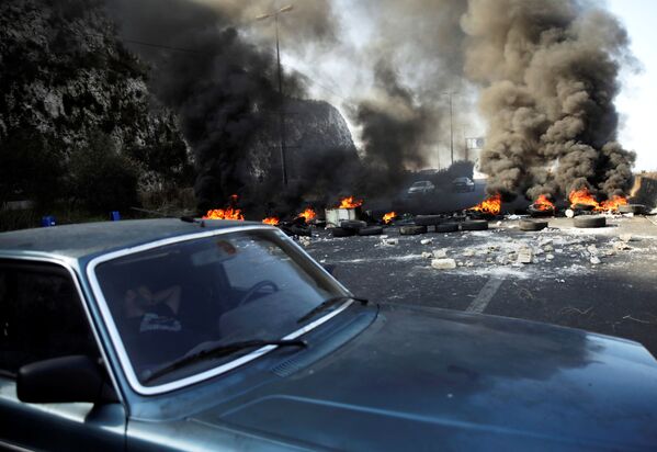 Người đàn ông ngủ trong chiếc ô tô bên cạnh những đống lửa lốp xe cháy trên đường cao tốc trong thời gian biểu tình chống chính phủ đang tiếp tục ở Nar Al-Kalb, Lebanon - Sputnik Việt Nam