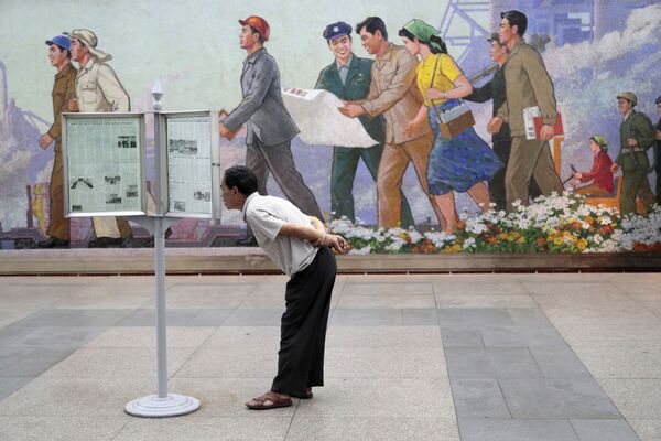 Hành khách tàu điện ngầm Bình Nhưỡng đứng đọc báo tường - Sputnik Việt Nam