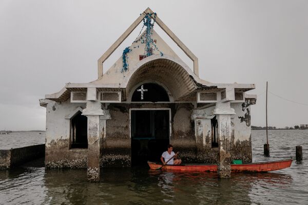 Người trông giữ nhà thờ bên cạnh nhà thờ bị ngập ở làng Sitio Pariahan, Philippines - Sputnik Việt Nam