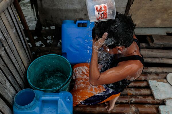 Cậu bé tắm rửa từ nguồn nước ngọt duy nhất tại ngôi làng bị ngập ở Philippines - Sputnik Việt Nam