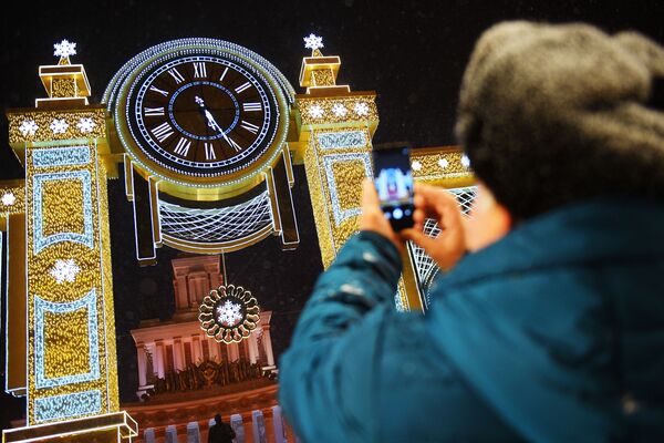Khách thăm VDNKh chụp ảnh đồng hồ “Giờ Giáng sinh” được đặt tại Gian chính - Sputnik Việt Nam