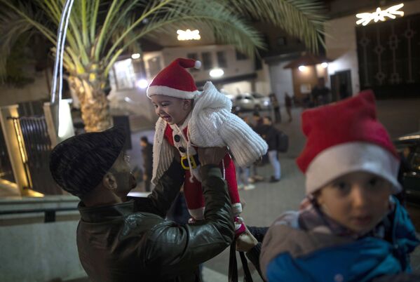 Người đàn ông chơi với đứa trẻ trước Thánh lễ Giáng sinh ở Gaza - Sputnik Việt Nam