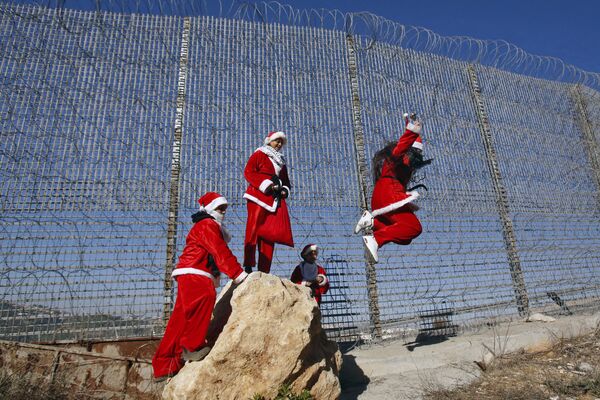 Những người Palestine mặc trang phục Giáng sinh nhảy từ vách đá bên hàng rào ngăn cách với Israel - Sputnik Việt Nam