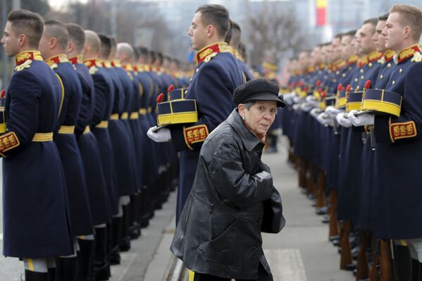 Người phụ nữ ngang qua Đội Cận vệ Danh dự trong lễ tưởng niệm tại Nghĩa trang anh hùng nhân kỷ niệm 30 năm cuộc nổi dậy chống cộng sản ở Romania - Sputnik Việt Nam