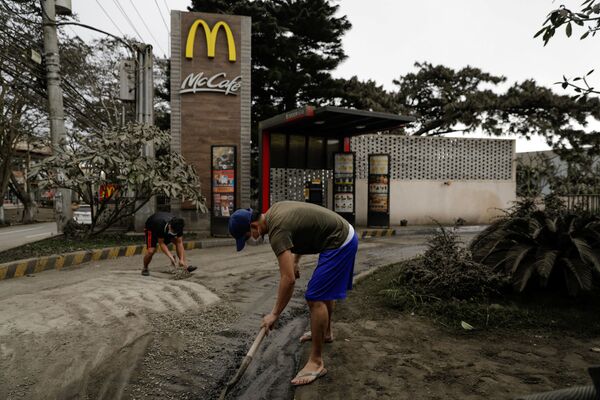 Các công nhân dọn tro núi lửa cạnh quán ăn McDonald's ở  thành phố Tagaytay, Philippines - Sputnik Việt Nam