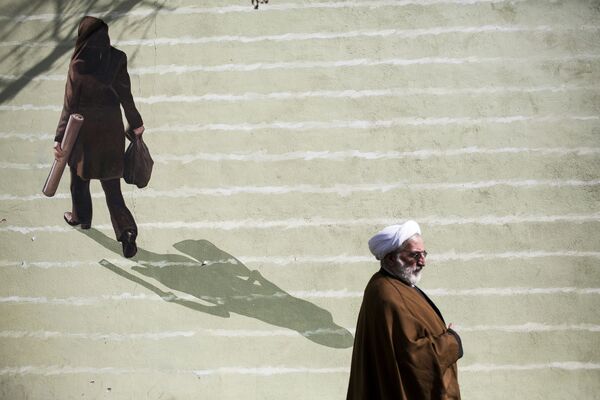 Vị giáo sĩ Iran đi ngang qua bức bích họa với chân dung phụ nữ ở trung tâm Tehran - Sputnik Việt Nam
