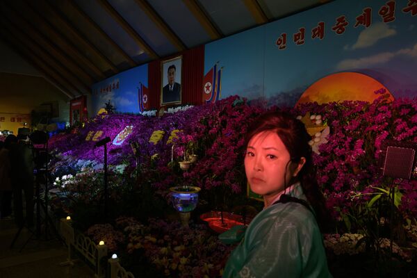 Nữ du khách dưới bức chân dung ông Kim Il Sung tại Triển lãm hoa nhân Ngày hội Mặt trời ở Bình Nhưỡng  - Sputnik Việt Nam