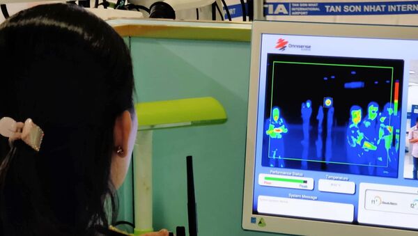 Nhân viên sân bay Tân Sơn Nhất kiểm tra màn hình hiển thị máy quét thân nhiệt đối với hành khách quốc tế đến Việt Nam. - Sputnik Việt Nam