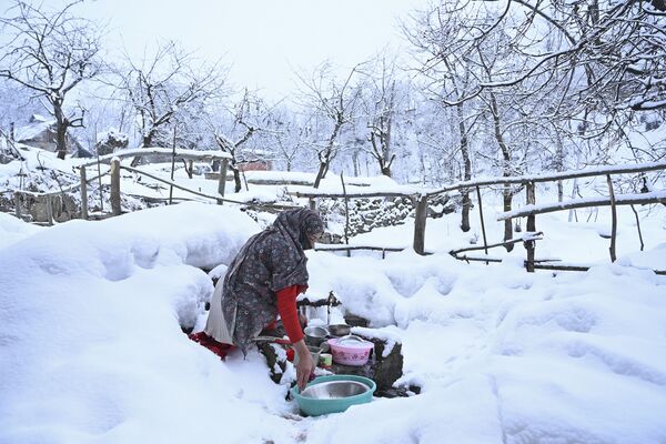 Người phụ nữ rửa chén đĩa ở ngoại ô Srinagar (Kashmir), nơi tuyết rơi - Sputnik Việt Nam