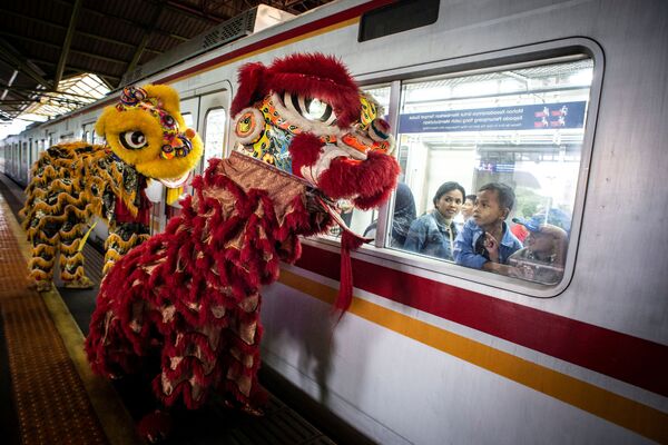 Hành khách xem múa sư tử qua cửa sổ xe lửa trong lễ đón Tết Nguyên đán tại Jakarta, Indonesia - Sputnik Việt Nam