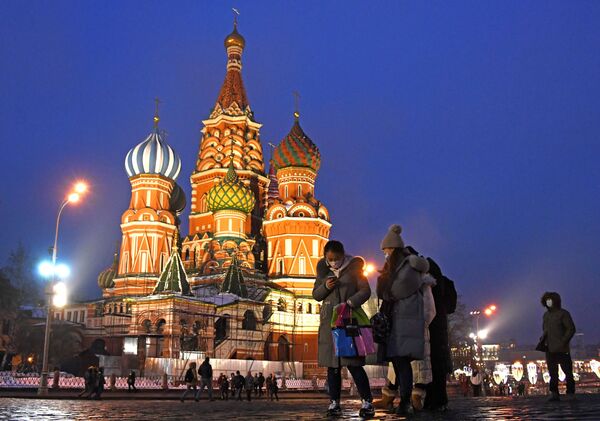 Khách du lịch nước ngoài đeo khẩu trang bảo vệ chụp ảnh gần Nhà thờ Thánh St. Basil trên Quảng trường Đỏ ở Moskva - Sputnik Việt Nam