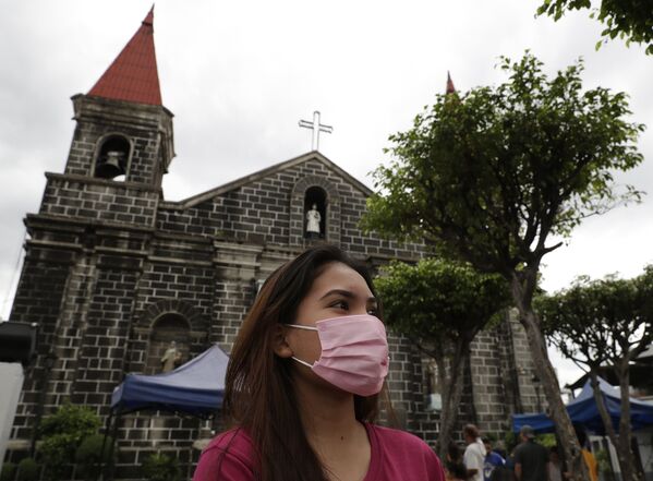 Người phụ nữ đeo khẩu trang ra khỏi nhà thờ ở Mandaluyong, phía đông Manila, Philippines - Sputnik Việt Nam