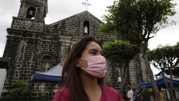 Người phụ nữ đeo khẩu trang ra khỏi nhà thờ ở Mandaluyong, phía đông Manila, Philippines - Sputnik Việt Nam