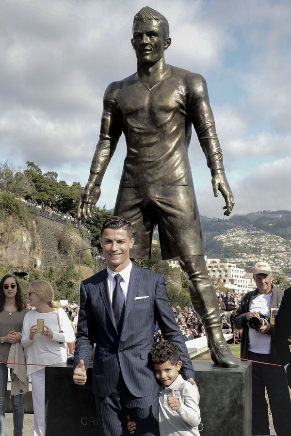 Cristiano Ronaldo cùng con trai dưới bức tượng danh thủ trong lễ khánh thành ở quê nhà Funchal, năm 2014 - Sputnik Việt Nam
