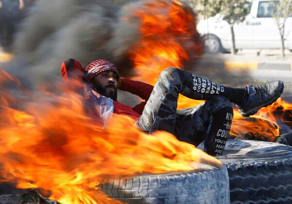 Người biểu tình giữa những chiếc lốp xe chặn đường đang bốc cháy trong cuộc biểu tình chống chính phủ ở Najaf, Iraq - Sputnik Việt Nam