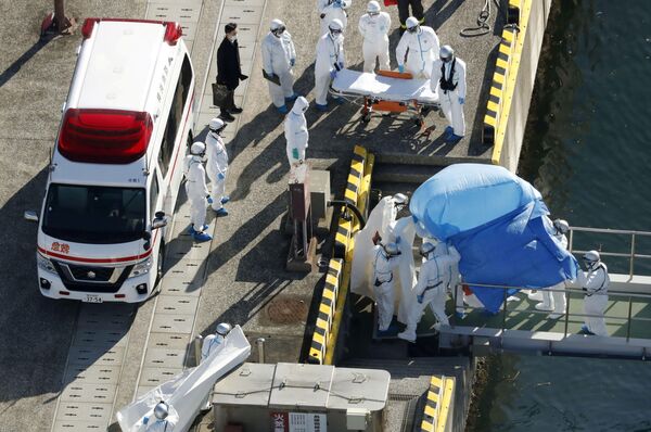 Các sĩ quan cảnh sát mặc đồ bảo hộ đưa hành khách bị bệnh trên tàu du lịch Diamond Princes lên xe cứu thương - Sputnik Việt Nam