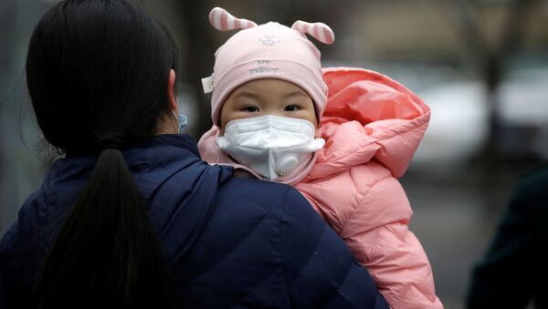 Một phụ nữ có con đeo mặt nạ y tế trên đường phố Bắc Kinh - Sputnik Việt Nam
