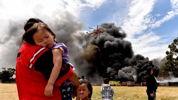 Người dân địa phương nhìn vào một chiếc trực thăng hạ xuống bên cạnh khói lớn từ đám cháy ở Melbourne - Sputnik Việt Nam