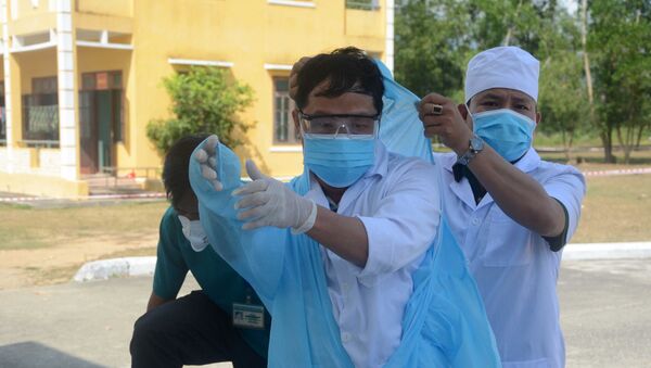 Cán bộ y tế mặc áo bảo hộ, khẩu trang trước khi vào chăm sóc sức khỏe cho các công dân được cách ly tại trung tâm.  - Sputnik Việt Nam