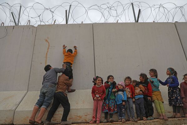 Trẻ em Syria trèo qua bức tường biên giới Thổ Nhĩ Kỳ ở tỉnh tây bắc Syria - Sputnik Việt Nam