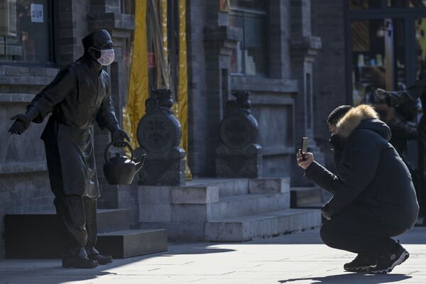 Người đàn ông chụp ảnh bức tượng đeo khẩu trang ở Bắc Kinh - Sputnik Việt Nam