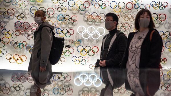 Người trong mặt nạ bảo vệ trên nền của các vòng tròn Olympic. Tokyo Nhật Bản - Sputnik Việt Nam