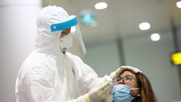 Nhân viên y tế lấy mẫu xét nghiệm của từng khách nhập cảnh ngay sau khi khách khai báo y tế và đo thân nhiệt. - Sputnik Việt Nam
