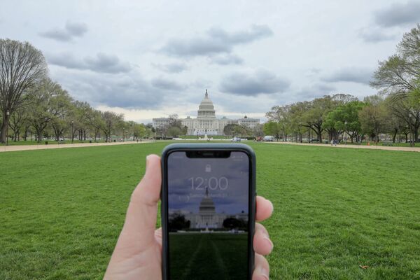 Đồng hồ chỉ 12 giờ trên điện thoại di động đối diện Tòa nhà Quốc hội Washington trong đại dịch coronavirus - Sputnik Việt Nam