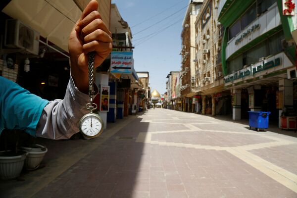 Chiếc đồng hồ bỏ túi chỉ 12 giờ trưa trên tay người đàn ông ở khu vực chợ gần nhà thờ Hồi giáo Imam Ali ở Najaf, Iraq, trong đại dịch coronavirus - Sputnik Việt Nam