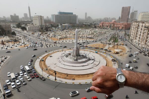 Đồng hồ đeo tay chỉ 12 giờ trưa trên nền Quảng trường Tahrir vắng người ở Cairo trong đại dịch coronavirus - Sputnik Việt Nam