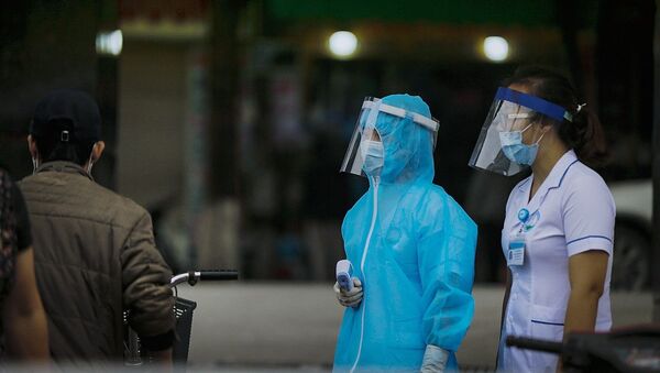 Lực lượng chốt bảo vệ đo thân nhiệt và khai báo ngay phía cổng bệnh viện cũng đang sử dụng chiếc mũ mà chị Vũ Thị Hoa làm ra. - Sputnik Việt Nam