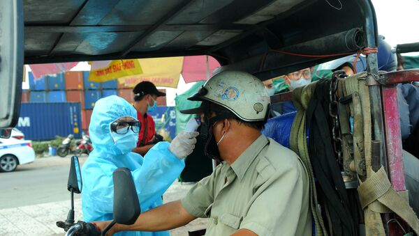 Lực lượng y tế kiểm tra thân nhiệt cho tài xế ra vào thành phố tại chân cầu Đồng Nai trên Xa lộ Hà Nội.  - Sputnik Việt Nam