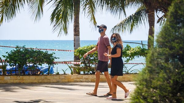 Khách du lịch đeo khẩu trang đi ngang qua một bãi biển đóng cửa giữa lúc dịch coronavirus bùng phát tại thành phố nghỉ mát Nha Trang, Việt Nam - Sputnik Việt Nam