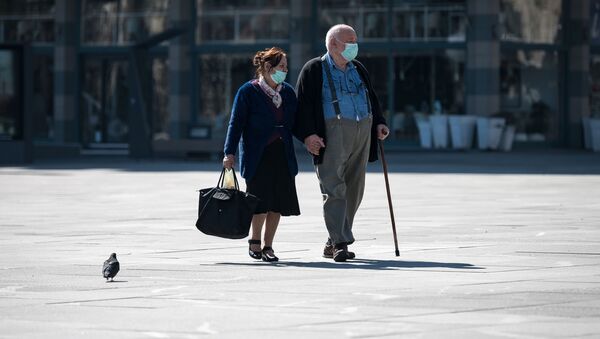 Một cặp vợ chồng người cao tuổi đeo khẩu trang trên đường phố Belgrade. - Sputnik Việt Nam