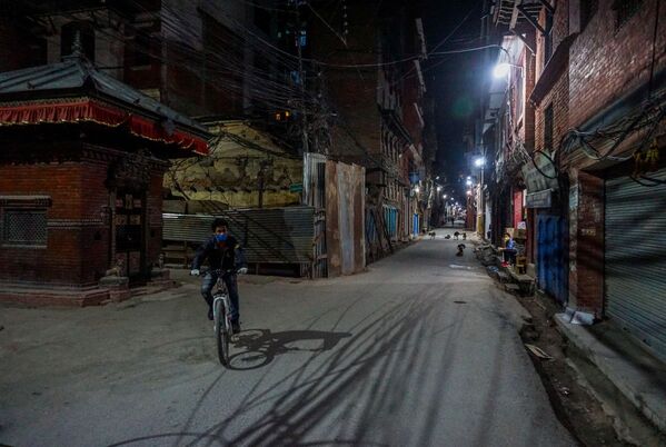 Người đàn ông đeo khẩu trang đi xe đạp dọc theo con đường ở ngoại ô thành phố Kathmandu - Sputnik Việt Nam