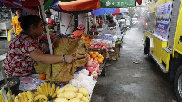 Nhân viên bán hàng đóng cửa trái cây từ việc phun thuốc tại một khu chợ ở Manila - Sputnik Việt Nam