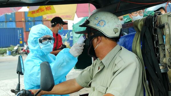 Nhân viên y tế đo thân nhiệt người ra vào thành phố Hồ Chí Minh tại chốt kiểm dịch. - Sputnik Việt Nam