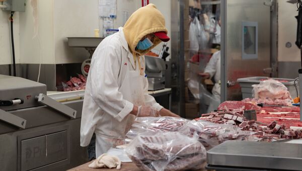 Người bán thịt xẻ thịt ở một khu chợ ở khu vực Bronx, New York. - Sputnik Việt Nam