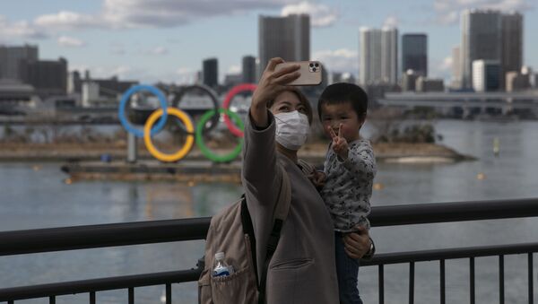 Người phụ nữ Nhật và con trai trên nền cảnh vòng tròn biểu tượng thế vận hội ở Tokyo - Sputnik Việt Nam