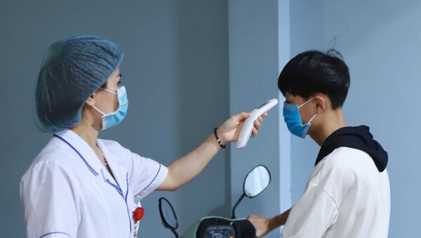 Lực lượng y tế đo thân nhiệt người dân khi vào bệnh viện. - Sputnik Việt Nam