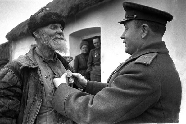 Chỉ huy sư đoàn trao giải cho nông trang viên Pomkin vì ông đã lập chiến công. Mặt trận 3 Ukraina. Năm 1945 - Sputnik Việt Nam