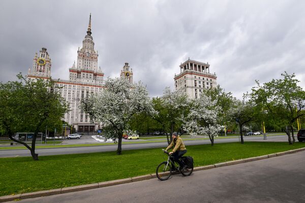 Người đi xe đạp trên nền cảnh hoa nở rộ gần tòa nhà Đại học quốc gia Moskva (MGU) - Sputnik Việt Nam