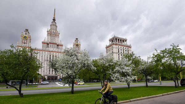 Người đi xe đạp trên nền cảnh hoa nở rộ gần tòa nhà Đại học quốc gia Moskva (MGU) - Sputnik Việt Nam